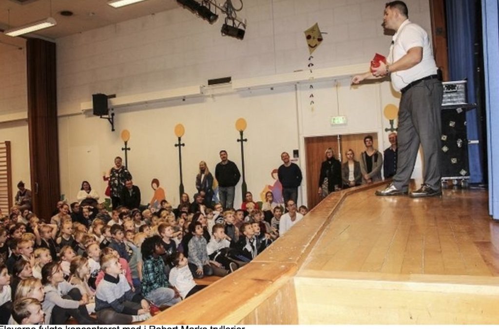 Børn ser trylleshow i en gymnastiksal